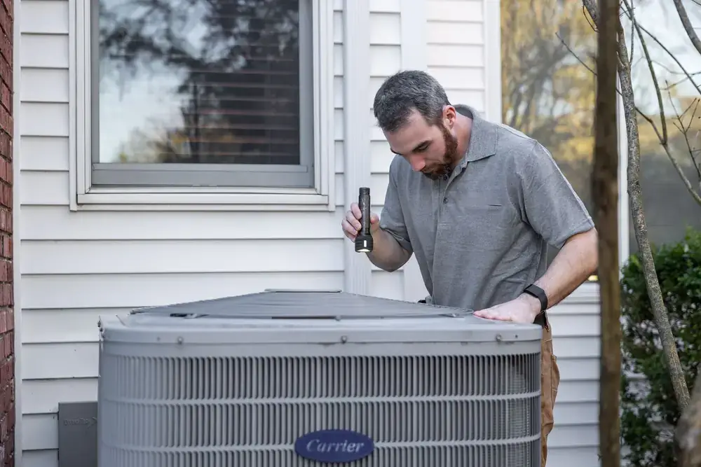 A technician inspecting an outdoor air conditioning unit