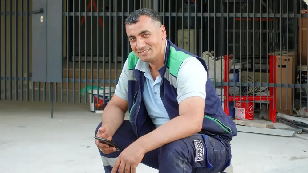 A smiling contractor checking his phone outdoors