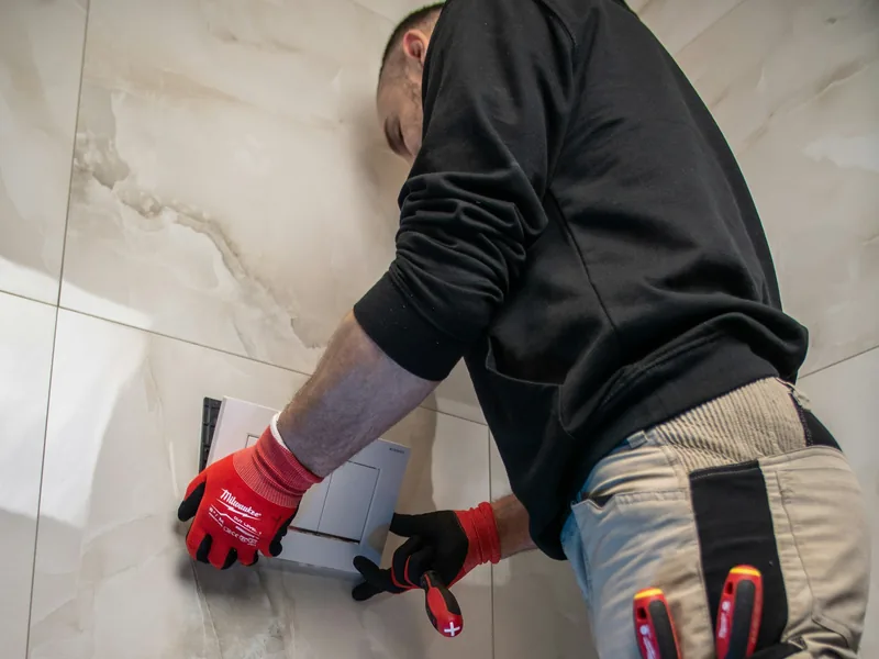 Uniformed plumber installing fixtures in a bright, clean bathroom